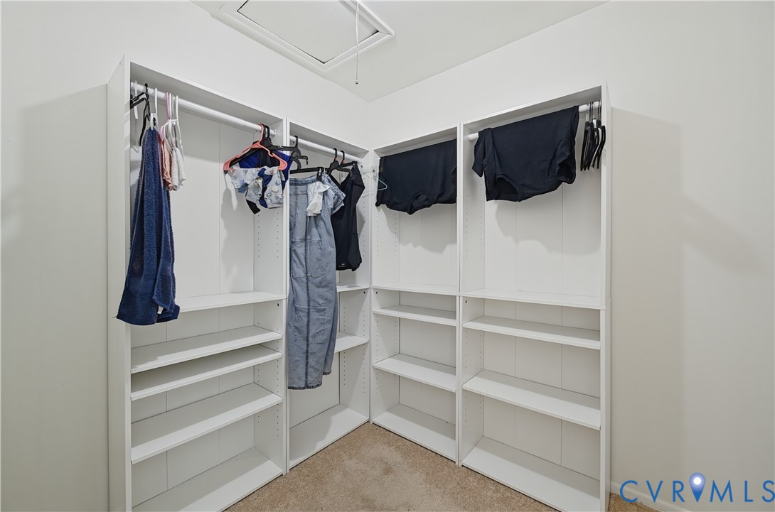 Walk-in closet featuring white built-in shelving units and integrated hanging rods