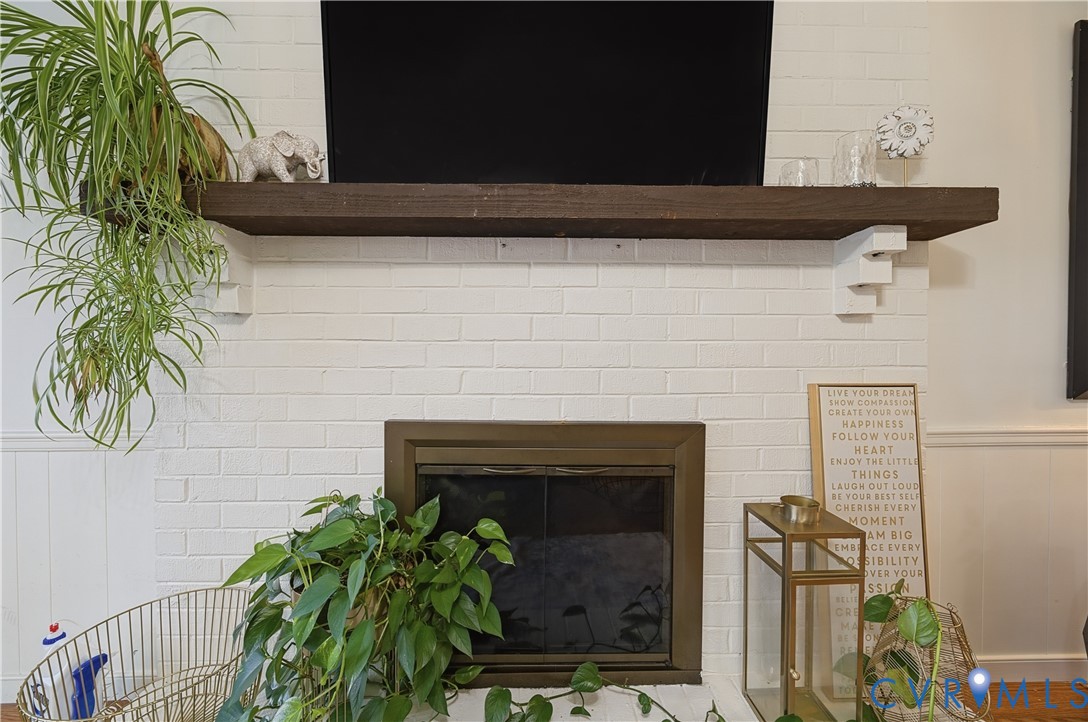 Fireplace featuring a painted white brick surround, dark-stained timber mantel, and metal glass-panel firebox enclosure