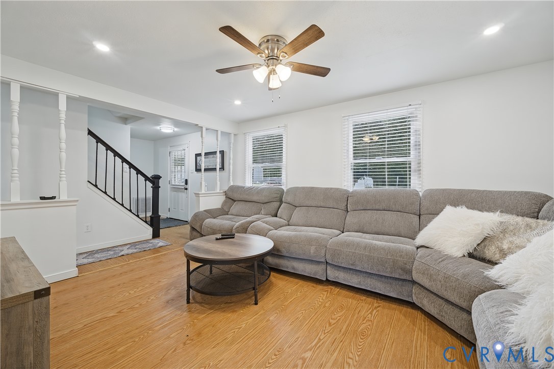 Wood-finish flooring, staircase with metal balusters, ceiling-mounted light fixture, recessed lighting, and horizontal window blinds Wood-finish flooring, staircase with metal balusters, ceiling-mounted light fixture, recessed lighting, and horizontal window blinds