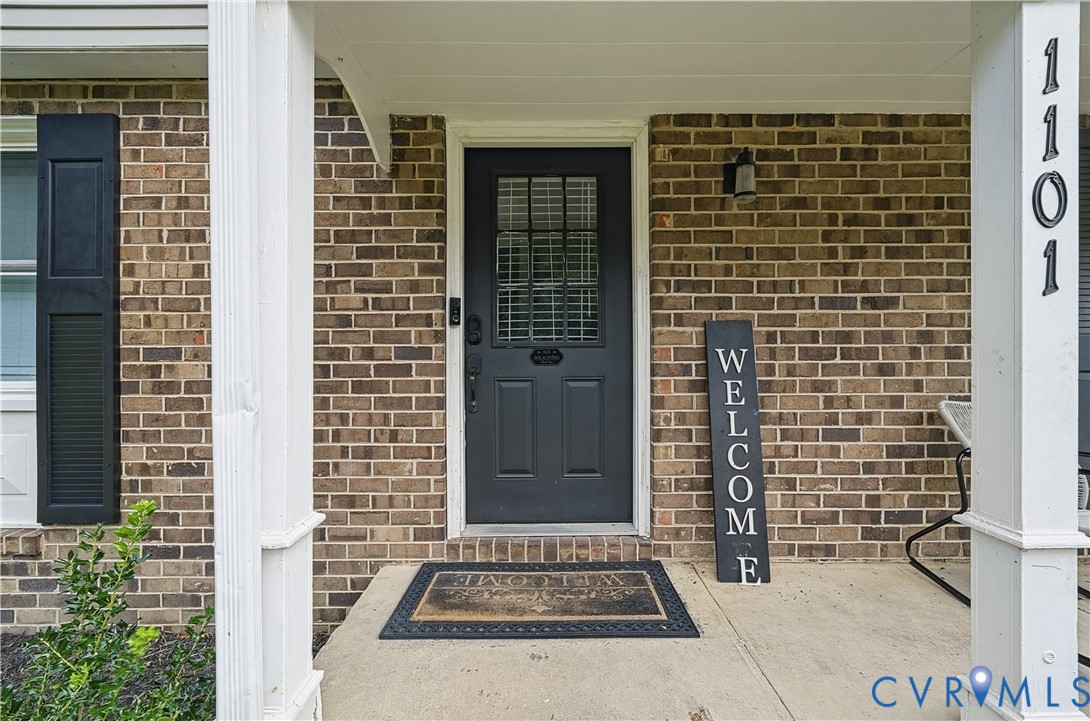 Covered front porch featuring a brick facade, decorative shutters, and a dark-toned door with window panes Covered front porch featuring a brick facade, decorative shutters, and a dark-toned door with window panes