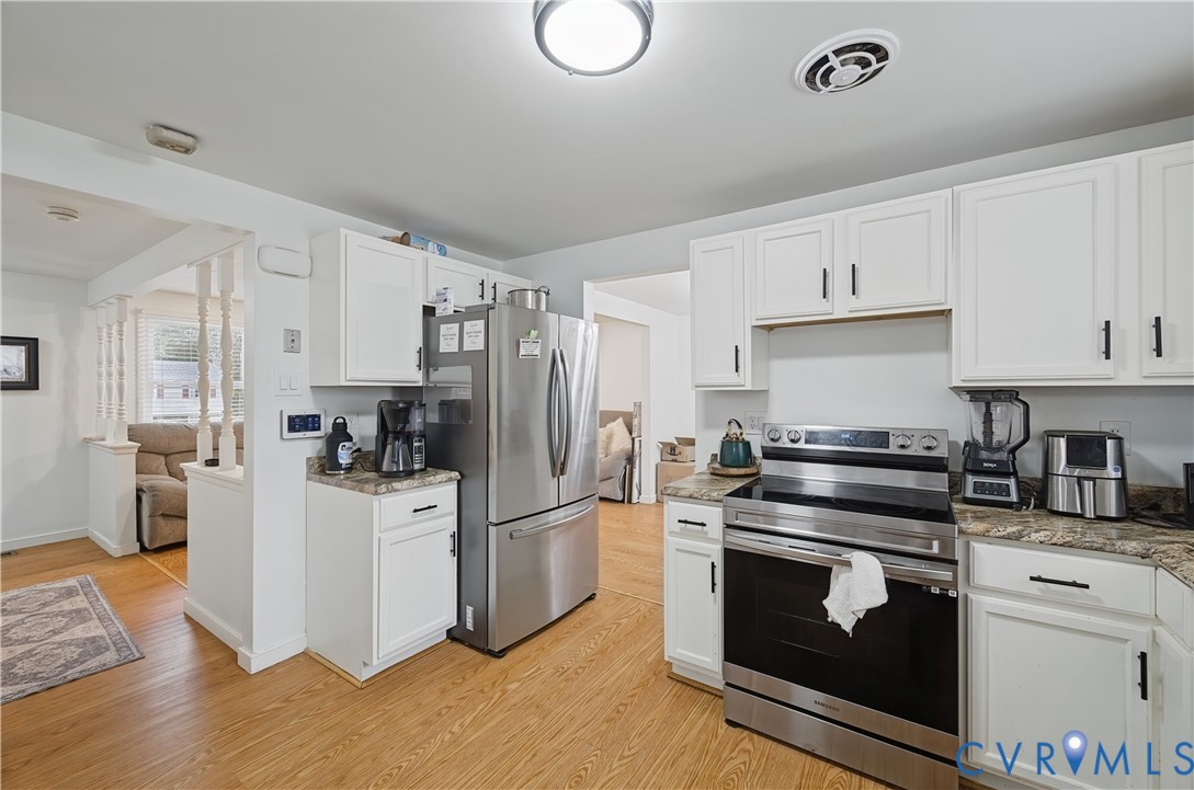 Kitchen featuring white cabinetry, stone-finish countertops, stainless steel appliances, and wood-finish flooring
