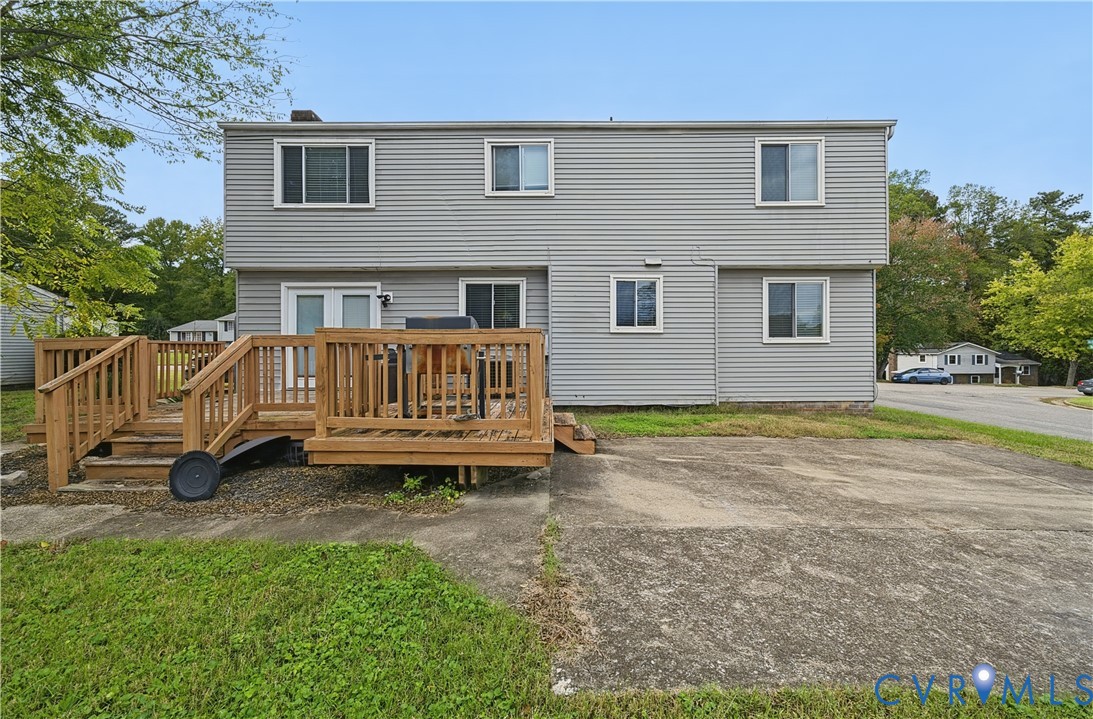 Two-story residence featuring light gray horizontal siding, an elevated wood deck, and a concrete patio