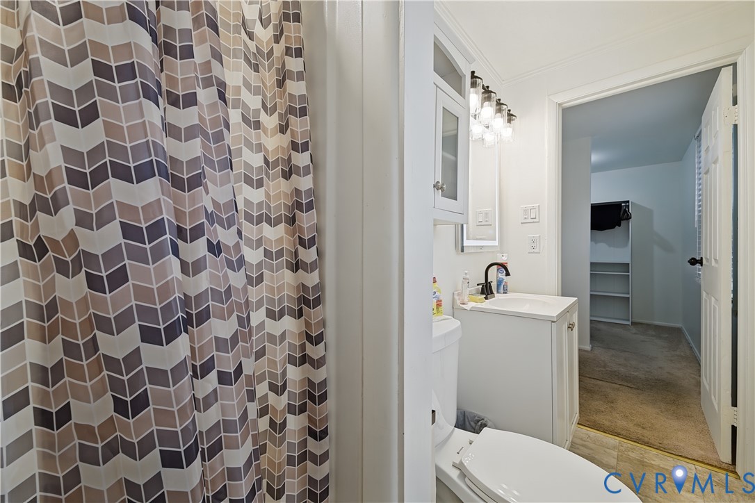 White vanity with integrated sink, oil-rubbed bronze finish faucet, multi-bulb vanity light fixture, and wall-mounted storage cabinetry