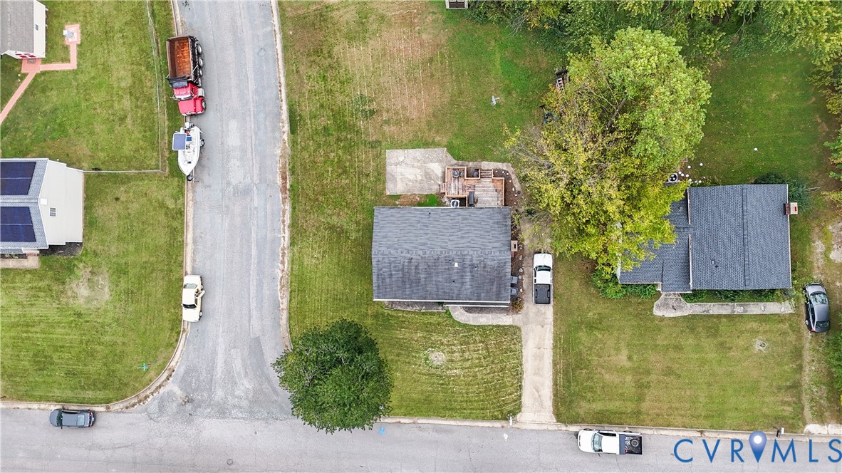 Aerial perspective featuring a residential lot with a concrete driveway and an outdoor wooden deck