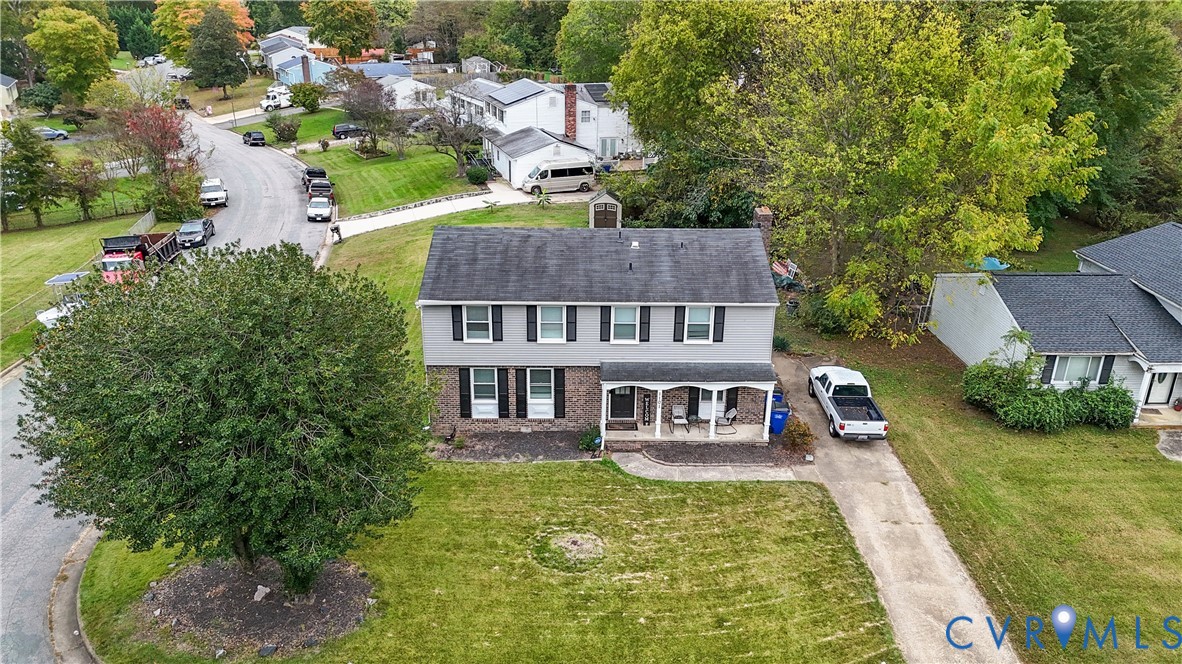 Two-story exterior featuring a brick facade, gray horizontal siding, an asphalt shingle roof, a covered front porch, and a concrete driveway