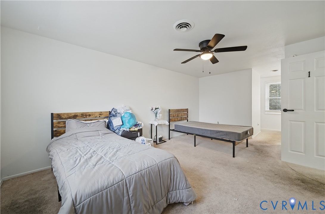 Neutral-toned bedroom featuring carpeted flooring, a ceiling fan with integrated lighting, and a six-panel door