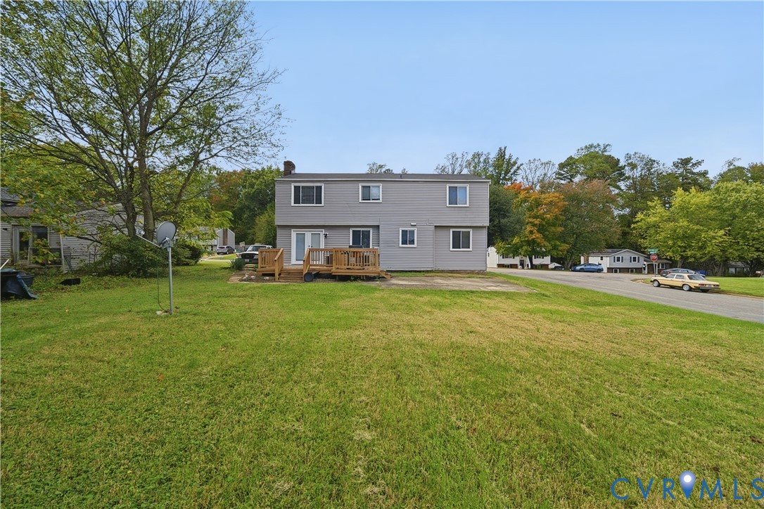 Two-story gray siding exterior featuring a wood deck and expansive lawn