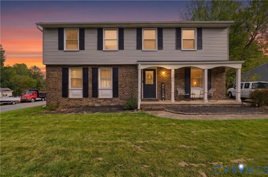 Two-story colonial exterior featuring a mixed brick and horizontal siding facade, covered front porch with arched supports, and decorative window shutters Two-story colonial exterior featuring a mixed brick and horizontal siding facade, covered front porch with arched supports, and decorative window shutters