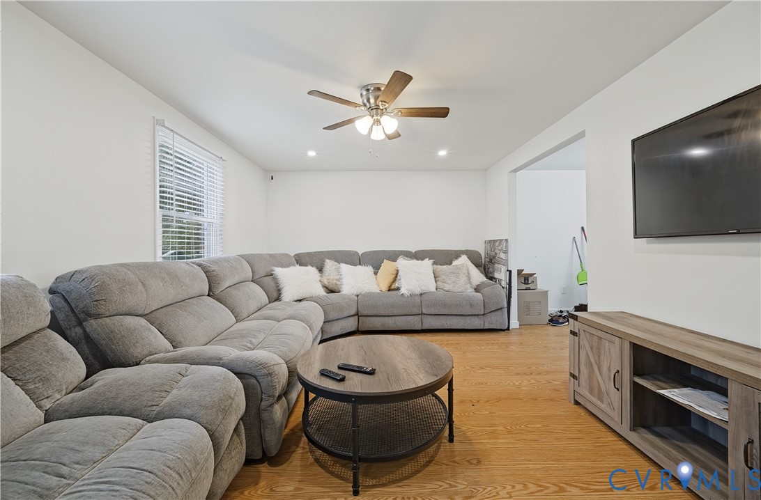 Living area featuring wood-finish flooring, a ceiling fan with integrated lighting, and recessed ceiling lights Living area featuring wood-finish flooring, a ceiling fan with integrated lighting, and recessed ceiling lights