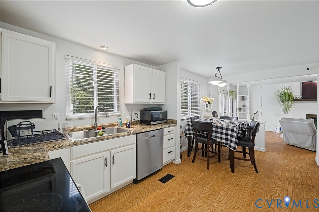 Kitchen featuring white cabinetry, stone-patterned countertops, stainless steel appliances, and wood-finish flooring