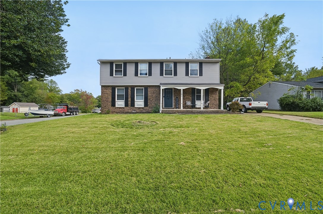 Two-story exterior featuring a brick and siding facade, covered front porch with arched supports, and black window shutters Two-story exterior featuring a brick and siding facade, covered front porch with arched supports, and black window shutters