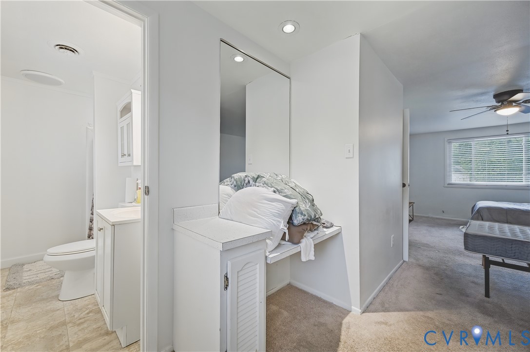 Built-in vanity with a countertop, full-height wall mirror, recessed ceiling lighting, and neutral-tone carpeting