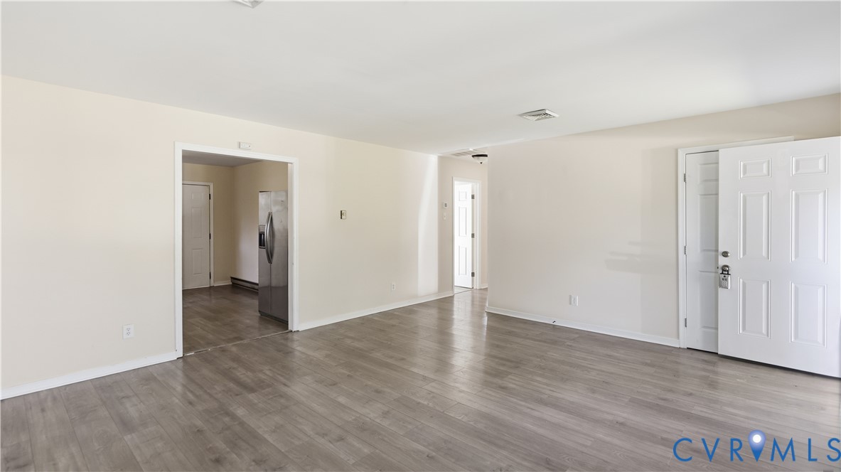 Neutral-toned walls, wood-finish flooring, and a six-panel entry door