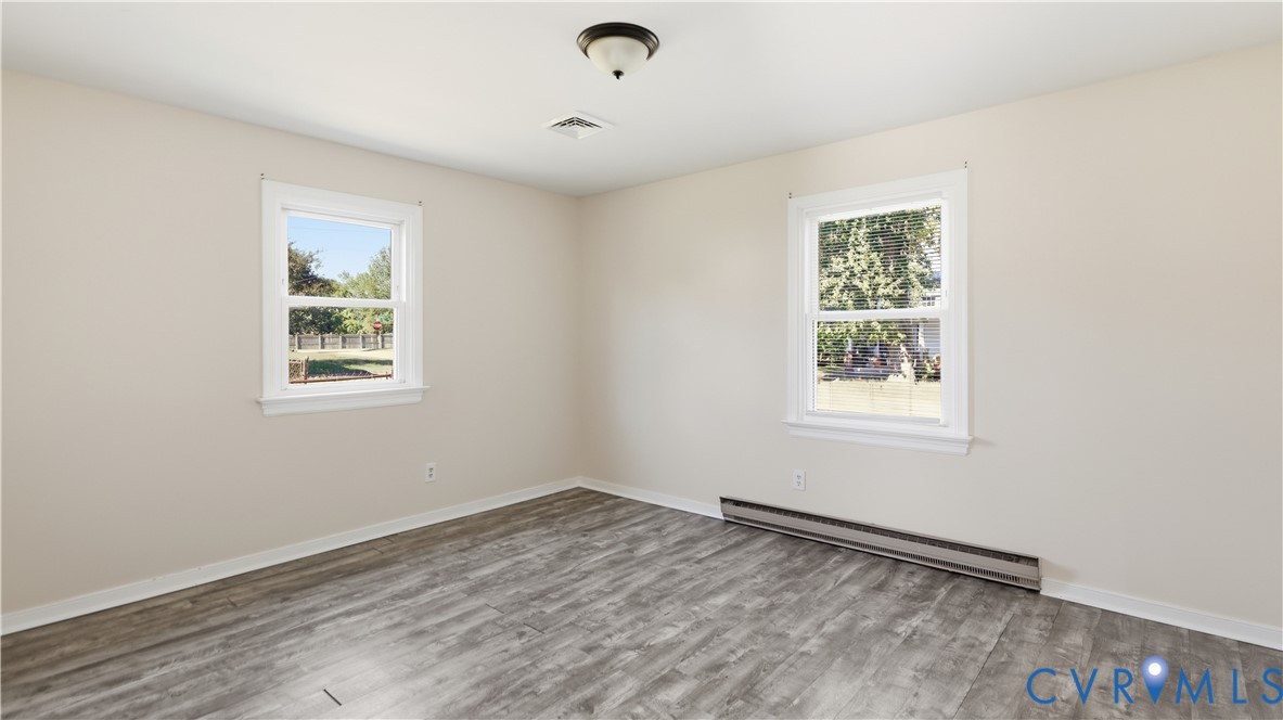 Neutral interior space featuring wood-finish flooring, dual windows, and a ceiling-mounted flush light fixture
