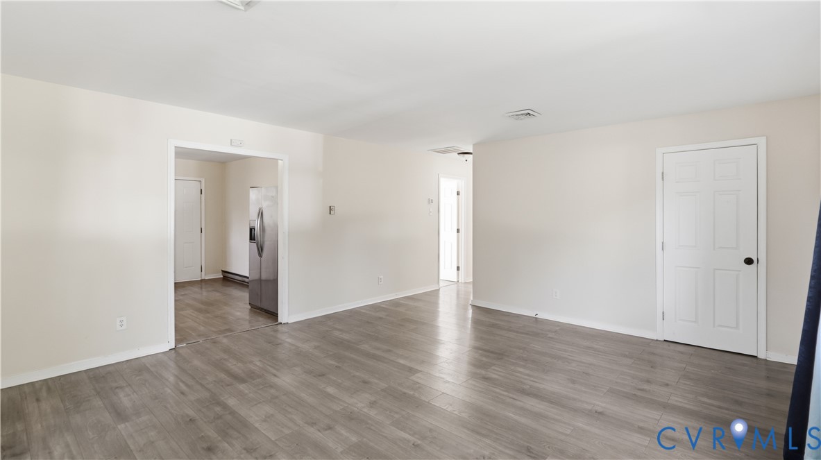 Interior space featuring neutral wall paint, wood-finish flooring, and white six-panel interior doors