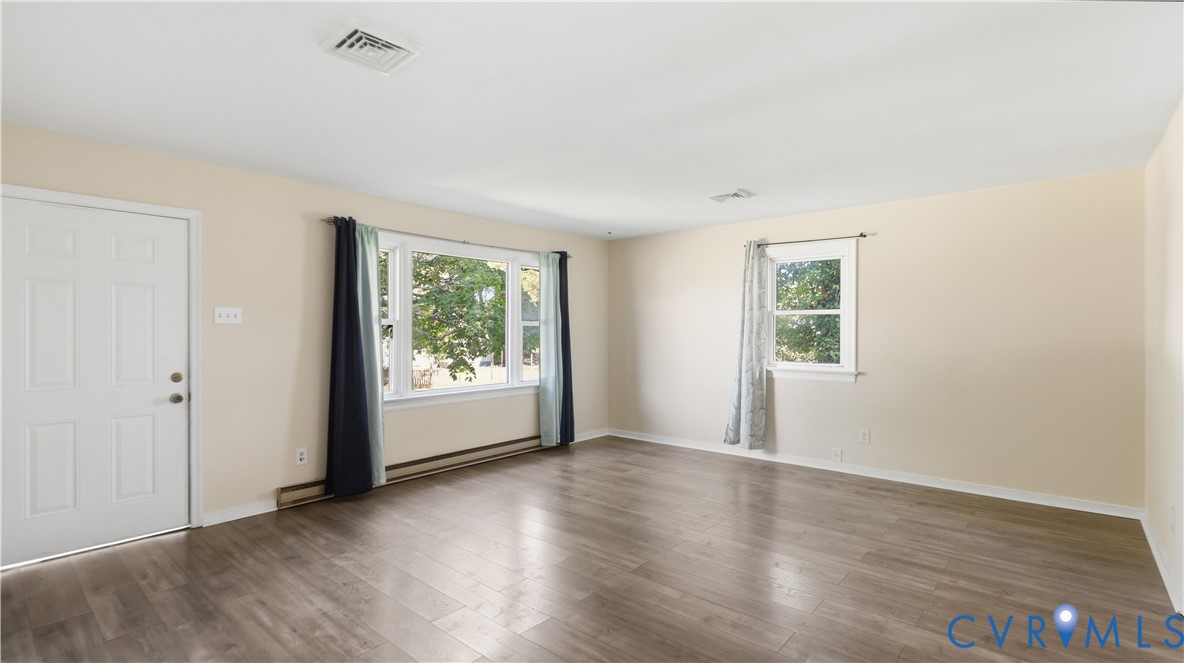 Interior space featuring wood-finish flooring, a large multi-pane picture window, and a secondary double-hung window
