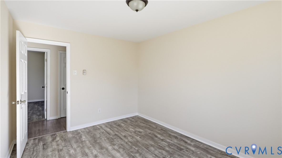Interior room featuring neutral wall paint, wood-finish flooring, and a flush-mount ceiling light fixture