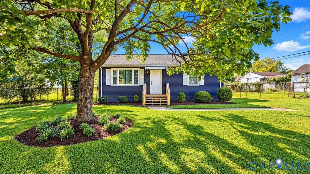 Single-story residence featuring navy horizontal siding, white louvered shutters, wooden porch stairs, and mature landscaping