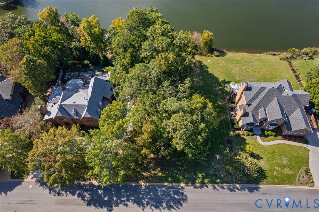 Aerial perspective of waterfront properties featuring extensive wooded buffers, multi-gabled rooflines, and paved driveways