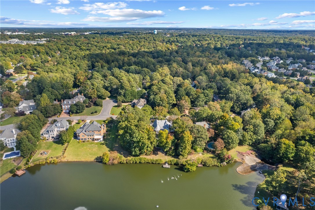 Aerial perspective of residential lots featuring water frontage, extensive tree coverage, and paved roadway access