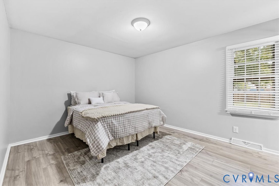 Neutral-toned walls, wood-finish flooring, and a single-pane window with white horizontal blinds Neutral-toned walls, wood-finish flooring, and a single-pane window with white horizontal blinds