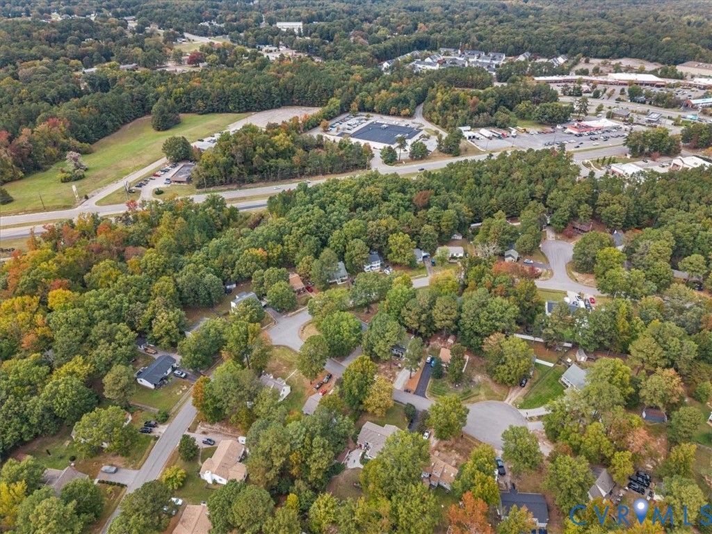 Aerial perspective of a residential neighborhood featuring mature canopy trees, winding paved streets, and expansive green space