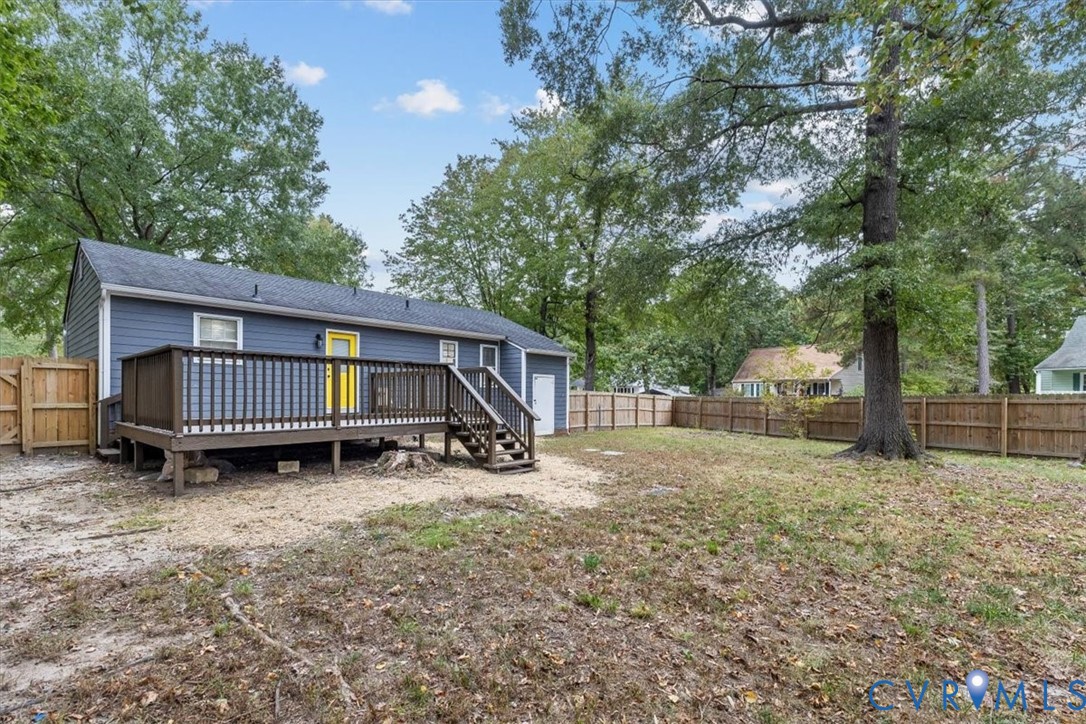 Rear exterior featuring a raised wood deck with stair access, horizontal lap siding, and a fully fenced perimeter with wood privacy fencing