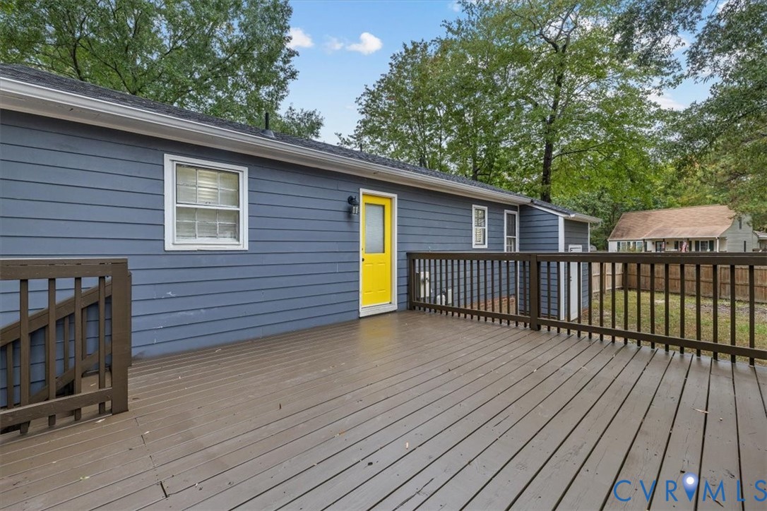Spacious elevated wood-finish deck with railings, blue horizontal siding, and an exterior door