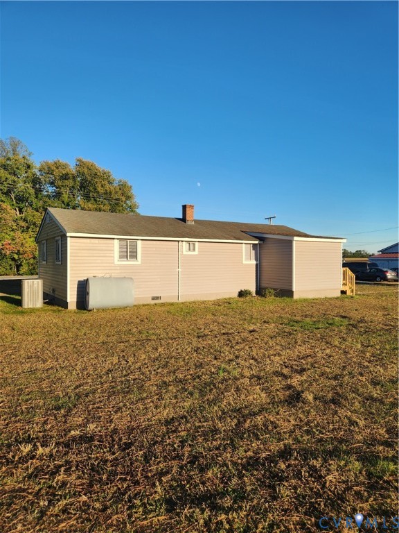 Exterior featuring horizontal siding, a central chimney, asphalt shingle roofing, and an expansive open lot