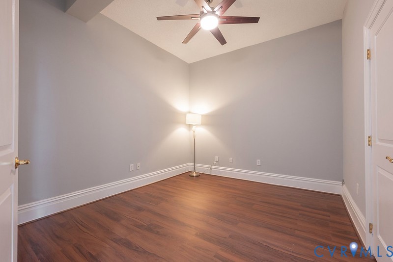 Room featuring wood-finish flooring, vaulted ceilings, and a ceiling fan with integrated light fixture