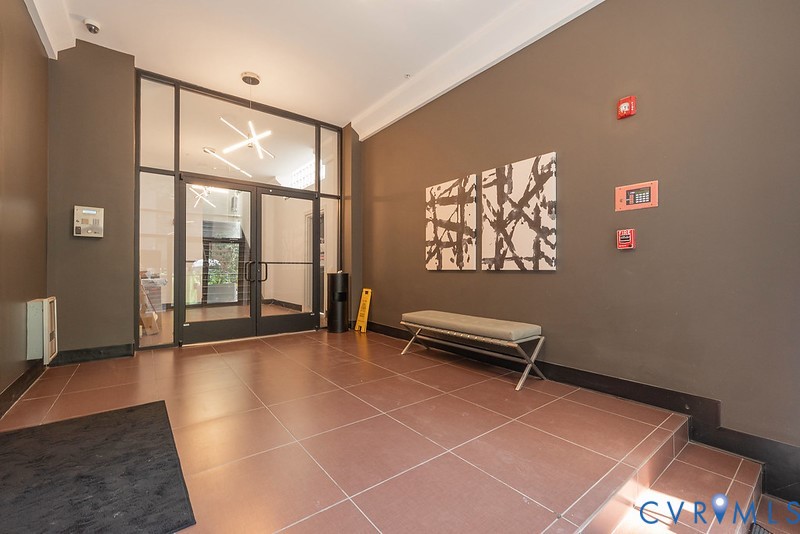 Building lobby featuring tile flooring, a glass-paned double entry door, geometric overhead lighting, and crown molding