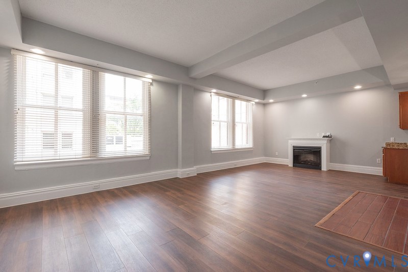 Living area featuring wood-finish flooring, recessed lighting, multi-pane windows, and a fireplace with a mantel