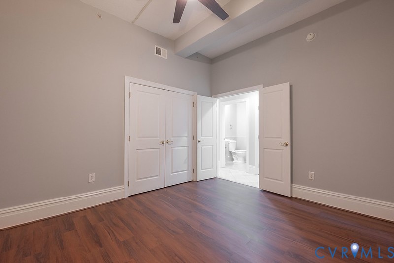 High ceilings featuring a dark-finish ceiling fan, wood-finish flooring, and white double-door closet cabinetry