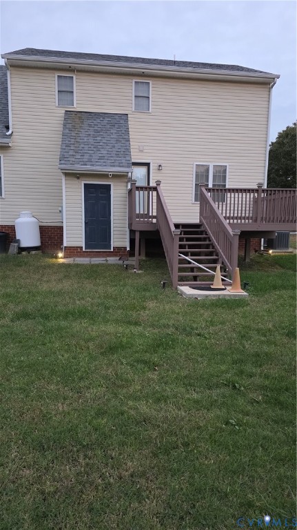 Rear exterior featuring light-colored horizontal siding, a raised wooden deck with staircase, brick foundation accents, and an open backyard Rear exterior featuring light-colored horizontal siding, a raised wooden deck with staircase, brick foundation accents, and an open backyard