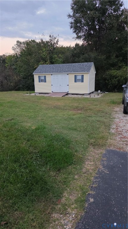 Detached storage building featuring vinyl siding, a gable roof with asphalt shingles, double entry doors, and decorative shutters Detached storage building featuring vinyl siding, a gable roof with asphalt shingles, double entry doors, and decorative shutters