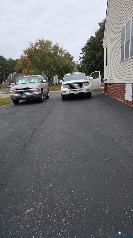Asphalt driveway with red brick foundation detailing and horizontal siding Asphalt driveway with red brick foundation detailing and horizontal siding