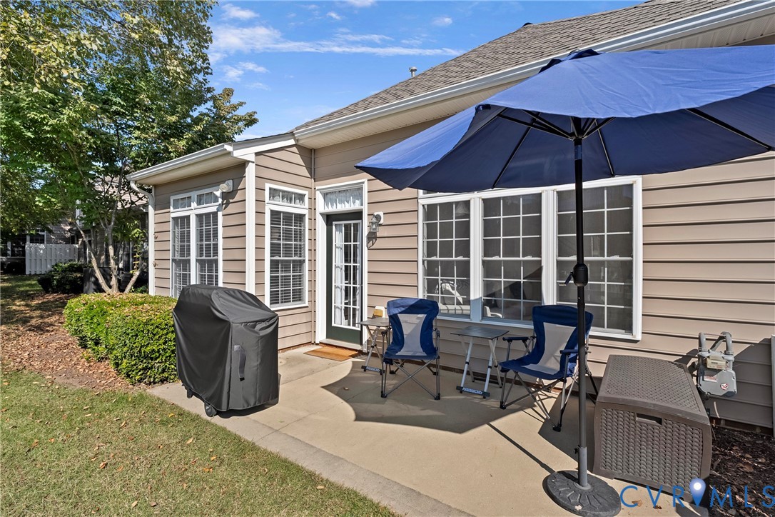 Concrete patio featuring horizontal vinyl siding, multi-pane windows, and a glass-paneled exterior door