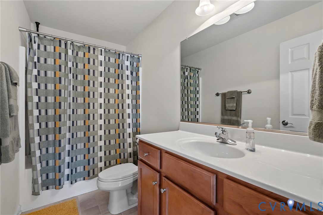 Bathroom featuring a full-width vanity mirror, wood-finish cabinetry, a white countertop with an integrated basin, single-handle chrome faucet, and a tub-shower combination