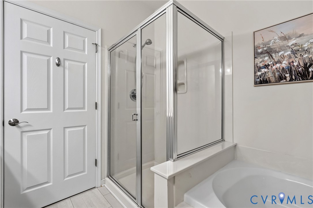 Glass-enclosed shower with chrome fixtures and integrated shelving, paired with a deep soaking tub and a six-panel solid core door