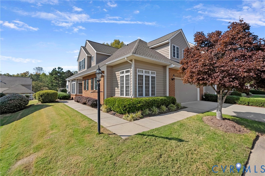 Multi-level exterior, brick masonry detailing, multi-gabled roofline, multi-pane windows, and a concrete driveway Multi-level exterior, brick masonry detailing, multi-gabled roofline, multi-pane windows, and a concrete driveway