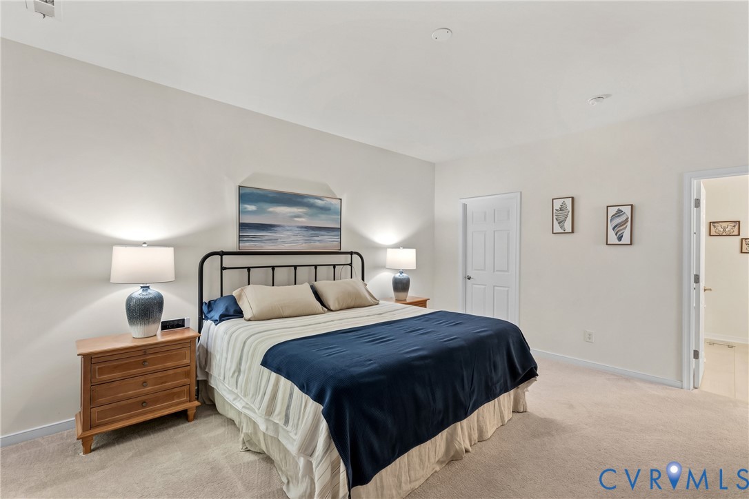 Primary suite with neutral-toned wall paint, recessed lighting, carpeting with en-suite luxury bath