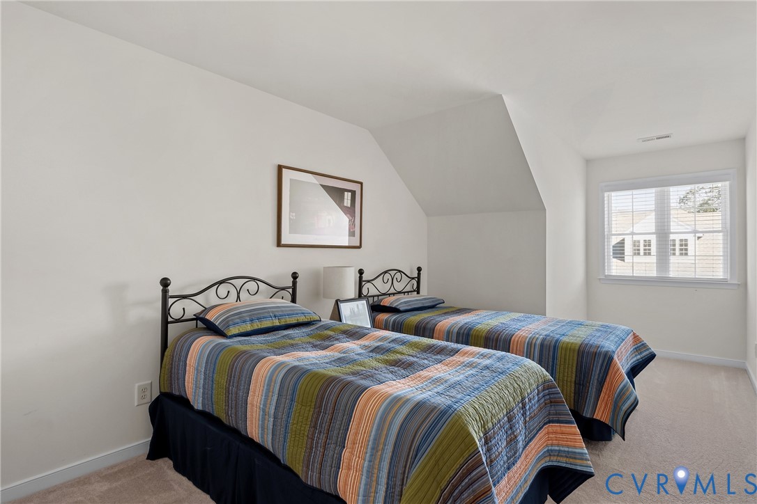 Vaulted ceiling, neutral wall tones, carpeted flooring, and a multi-pane window