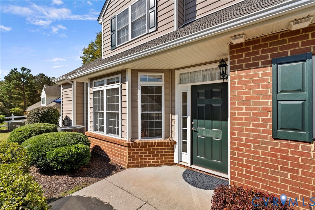 Exterior featuring a covered entry with a dark green paneled door, multi-pane windows with decorative shutters. Exterior featuring a covered entry with a dark green paneled door, multi-pane windows with decorative shutters.