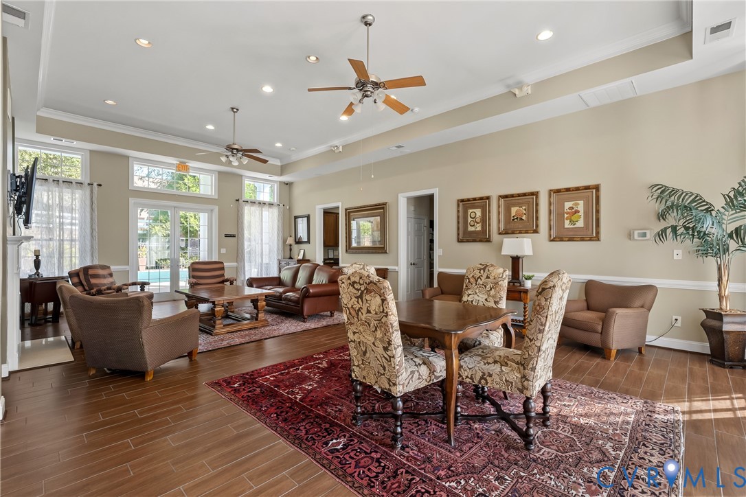 Community Clubhouse open-concept space featuring tray ceilings, recessed lighting, wood-finish tile flooring, dual ceiling fans, and glass paneled doors