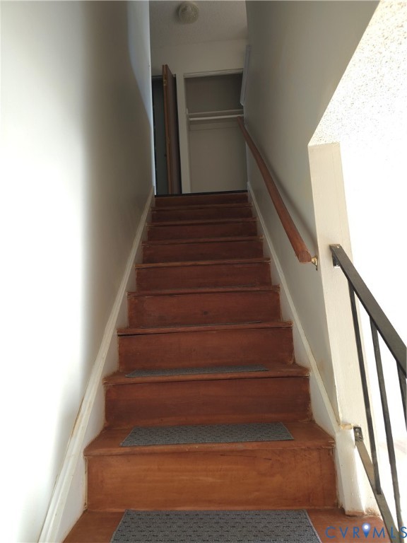 Staircase featuring wood-finish treads and a metal handrail Staircase featuring wood-finish treads and a metal handrail
