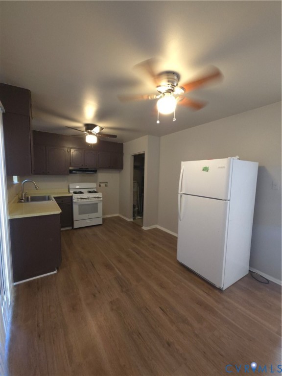 Kitchen featuring dark cabinetry, wood-finish flooring, white gas range, and dual ceiling fans Kitchen featuring dark cabinetry, wood-finish flooring, white gas range, and dual ceiling fans