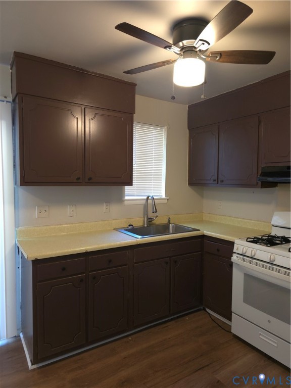 Kitchen featuring dark cabinetry, solid-surface countertops, stainless steel sink with high-arc faucet, wood-finish flooring, and ceiling-mounted light fixture Kitchen featuring dark cabinetry, solid-surface countertops, stainless steel sink with high-arc faucet, wood-finish flooring, and ceiling-mounted light fixture