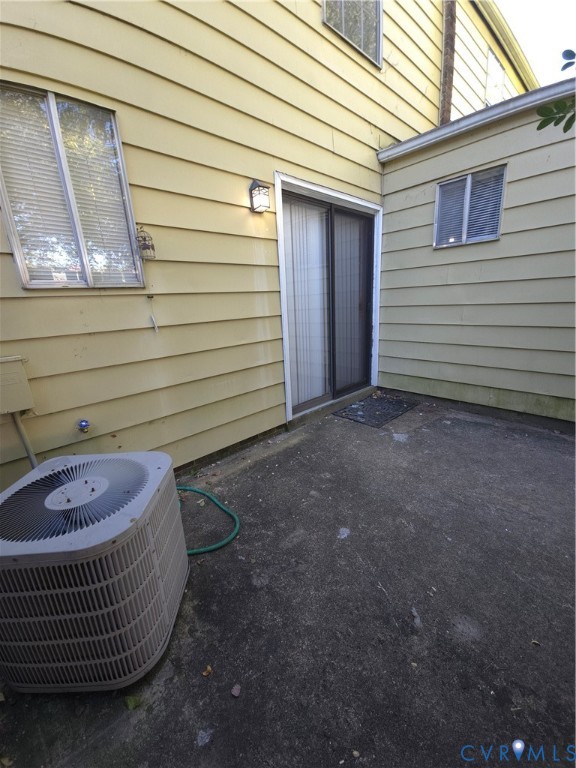 Exterior siding, sliding glass door with integrated screen, concrete patio, and wall-mounted exterior lighting Exterior siding, sliding glass door with integrated screen, concrete patio, and wall-mounted exterior lighting