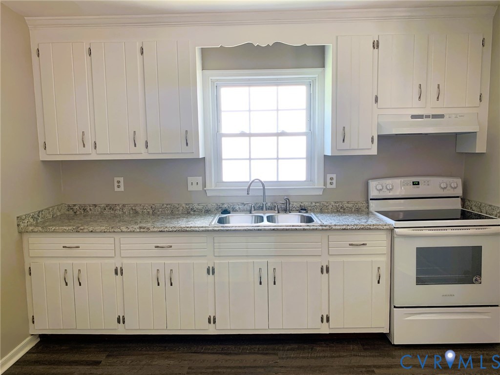 Kitchen featuring white cabinetry, stone-finish countertops, a dual-basin stainless steel sink, a range with an integrated hood, and wood-finish flooring