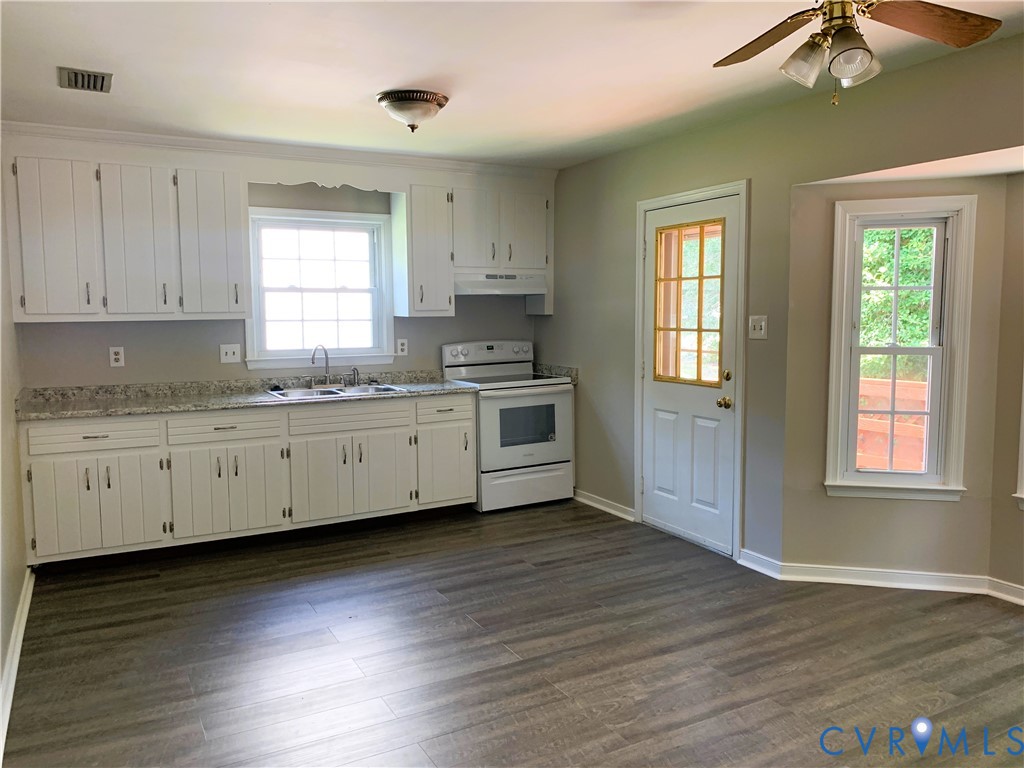 Kitchen featuring white cabinetry, stone-finish countertops, wood-finish flooring, a multi-pane exterior door, and a bay window
